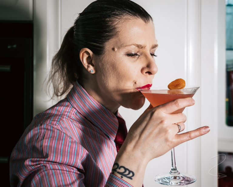 Taking the first sip from an Apricot Cosmo cocktail